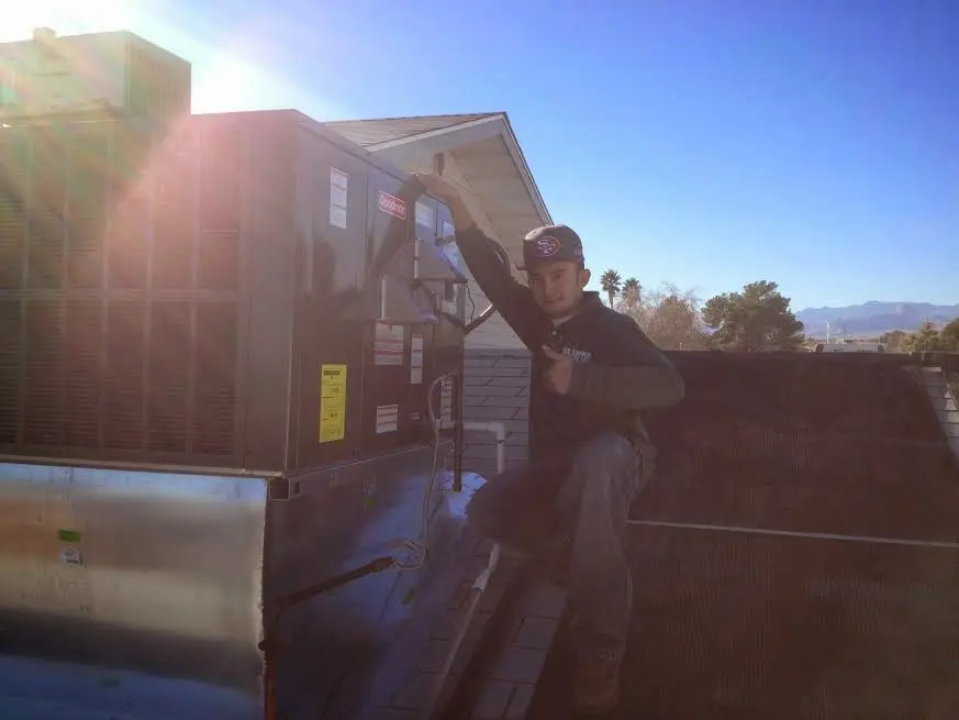 HVAC technician performing AC Tune-Up on a rooftop unit in Security-Widefield